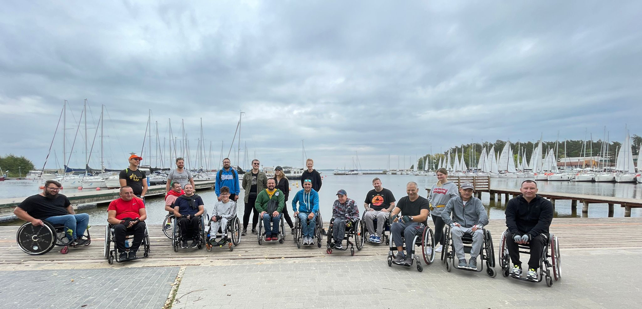 Nad jeziorem Niegocin – grupowe zdjęcie uczestników obozu Aktywnej Rehabilitacji w Wilkasach 24.09-05.10.2023