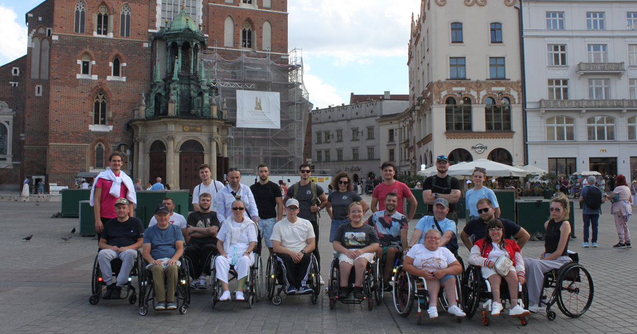 Dziesięcioro uczestników i kadra obozu Aktywnej Rehabilitacji na rynku w Krakowie, 23.08-3.09.2025 r.