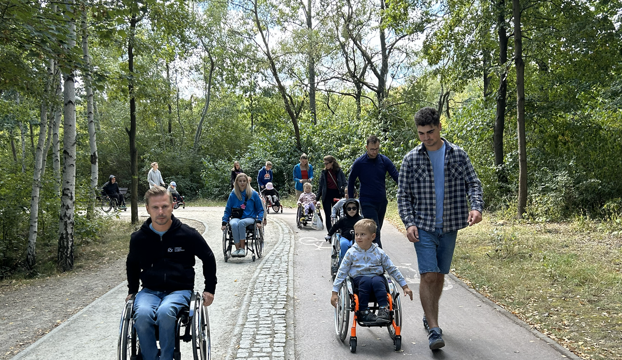 Spacer w parku. Uczestnicy i kadra Warsztatu Aktywnej Rehabilitacji dla dzieci i rodziców w Katowicach, 22-24.08.2025 r.