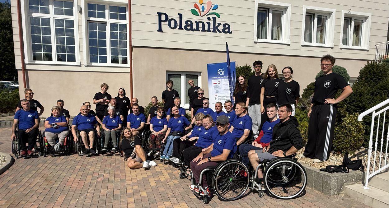 Uczestnicy i kadra Obozu Aktywnej Rehabilitacji, 26.08-06-09.2026, przed wejściem do Ośrodka Rehabilitacyjnego Polanika w Chrustach.